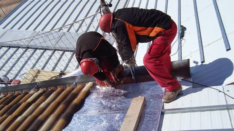 צוות מתקין ומאבטח שכבת בידוד רפלקטיבי במהלך עבודות גג San Bodega