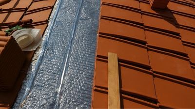 שכבת בידוד רפלקטיבית מותקנת בין שורות רעפים על גג רעפים לפני סגירת הכיסוי