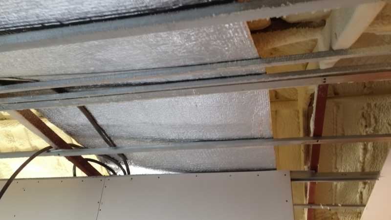 לחיצה להגדלת תמונה תקרת עליית גג בתהליך התקנה עם יריעת בידוד רפלקטיבית וקונסטרוקציית מתכת חשופה