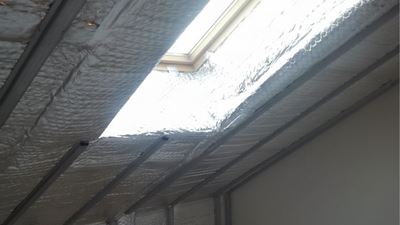 תקרת עליית גג עם יריעת בידוד רפלקטיבית הפרוסה סביב חלון סקיילייט גדול