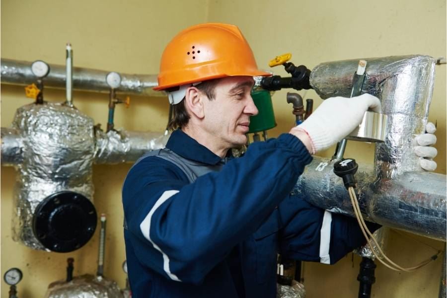 טכנאי מתקין בידוד אלומיניום על מערכת צינורות.