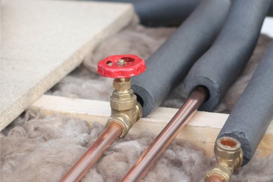 צנרת נחושת עם בידוד מוקצף ושסתום אדום חשוף.