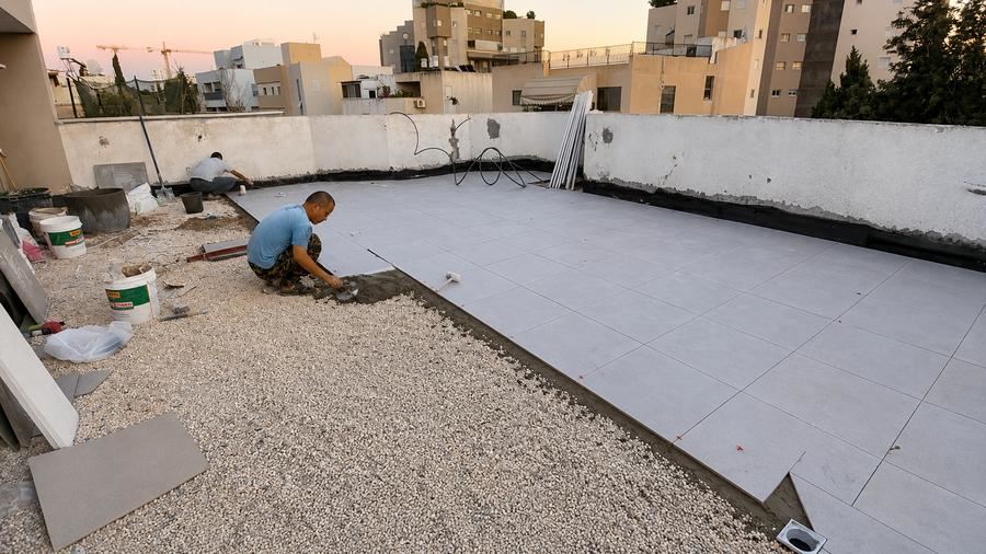 פועלים מרצפים גג לאחר התקנת שכבת בידוד תרמי
